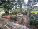 Secluded backyard picnic area featuring stone table, seats and umbrella under mature trees at 1408 Torrey Pines Dr, Lady Lake, FL 32159