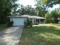 Well-kept home with a lush lawn, attached garage, and inviting screened porch entrance at 19026 Sw 100Th Pl, Dunnellon, FL 34432