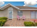 Inviting front porch with patterned tile, pink Adirondack chairs, and neat landscaping at 21 Pine Trace Run, Ocala, FL 34472