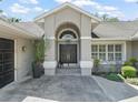 Elegant home entrance with a black double door, arched transom window, and decorative plants and gravel at 5714 Nw 80Th Avenue Rd, Ocala, FL 34482