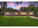 A beautifully lit one-story home with brick accents, a green lawn, and a colorful evening sky at 6060 Se 119Th Pl, Belleview, FL 34420