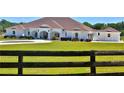 Charming white single-story home surrounded by lush greenery and a wooden fence at 6160 W Highway 326, Ocala, FL 34482