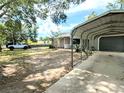 Exterior view of the home showing the covered parking area, fenced backyard and mature trees at 70 Almond Pass Dr, Ocala, FL 34472