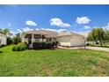 A sunny single-story home featuring lush green lawn, mature landscaping, and an attached garage at 8352 Se 168Th Trinity Pl, The Villages, FL 32162
