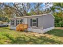 Single story home featuring low wood porch, gray siding, and black window shutters at 9100 Sw 32Nd Ct, Ocala, FL 34476