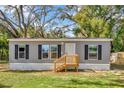 Single story home features low wood porch, gray siding, and black window shutters at 9100 Sw 32Nd Ct, Ocala, FL 34476