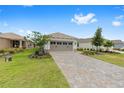 A well-manicured front yard and long driveway leading to a charming single-story home with a neutral color palette at 10427 Sw 98Th Place Rd, Ocala, FL 34481