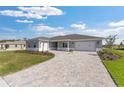 Beautiful single-story home featuring a paved driveway, neutral paint, and a well-maintained lawn on a sunny day at 10976 Sw 101St Loop, Ocala, FL 34481