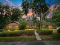 Charming single-story home with a manicured lawn, mature trees, and welcoming walkway at dusk at 2416 Se 15Th St, Ocala, FL 34471