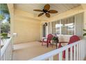 Covered front porch with white railing, ceiling fan, and two chairs for relaxation at 8710 Sw 91St St # E, Ocala, FL 34481