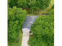 An aerial shot of a gray roofed home, surrounded by lush green trees and a long driveway at 8926 Sw 192Nd Court Rd, Dunnellon, FL 34432