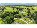 Expansive aerial view of a home with a lush green landscape, a large pond, and neighboring horse pastures at 8940 Sw 8Th St, Ocala, FL 34481