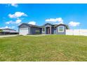 Single-story gray home with a two-car garage, well-kept lawn, and a red front door at 10291 Se 67Th Ter, Belleview, FL 34420