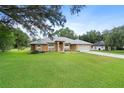 Attractive single-story house featuring an arched doorway, gray roof, green lawn and long concrete driveway at 10716 Sw 53Rd Cir, Ocala, FL 34476