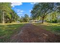 Exterior of property featuring a long driveway, mature trees, and gray paint at 11521 Se 1St Street Rd, Silver Springs, FL 34488