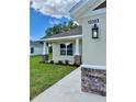 Home exterior showcasing manicured lawn, stone accents, and a covered entryway with stylish lighting at 13303 Sw 106Th Pl, Dunnellon, FL 34432
