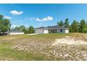 Spacious yard surrounding a home with a two-car garage, set against a bright blue sky at 13561 Sw 85Th Pl, Dunnellon, FL 34432