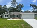 Charming single-story home featuring a well-manicured lawn and attached two-car garage at 4105 Se 138Th Pl, Summerfield, FL 34491