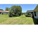 Expansive backyard featuring a lush green lawn, mature trees, and partial view of neighboring houses at 8239 Sw 108Th St, Ocala, FL 34481