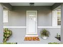 Close-up of the front door, featuring a decorative welcome mat and potted plants at 9729 Sw 97Th St, Ocala, FL 34481