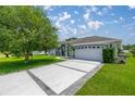 Home exterior featuring a long driveway and a two-car garage on a landscaped lawn at 11140 Sw 53Rd Cir, Ocala, FL 34476