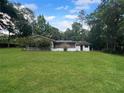 Expansive backyard featuring lush green lawn and mature trees surrounding the home at 11230 Se 47Th Ave, Belleview, FL 34420