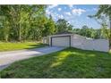 View of the home showing its white vinyl fence, spacious lawn, and attached two car garage at 13314 Se 41St Ct, Belleview, FL 34420