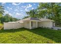 Side view of the home featuring a white exterior, fenced yard, and manicured lawn at 13314 Se 41St Ct, Belleview, FL 34420