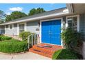 Close-up of a striking double blue front door with brick steps and lush, green landscaping around the entrance at 1404 Se 40Th Ct, Ocala, FL 34471