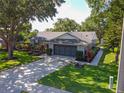 Single story home with mature trees, well-maintained lawn and long driveway to a 2-car garage at 15917 Hidden Lake Cir, Clermont, FL 34711