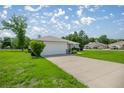 View of the side of a home with a two car garage and long drive way in a green neighborhood at 16062 Se 89Th Ter, Summerfield, FL 34491