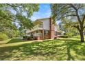 Expansive side view showcases a two-story home with brick accents, a covered balcony, and a well-maintained lawn at 20861 Sw 81St Loop, Dunnellon, FL 34431