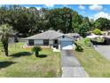 Aerial view of a charming single-story home with a stone facade, lush greenery, and a private driveway at 5060 Ne 4Th St, Ocala, FL 34470