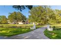 Home entrance with a long driveway, gated entry, lush lawn, and mature landscaping at 6381 Sw 21St Court Rd, Ocala, FL 34471