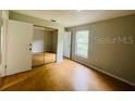 Bedroom featuring a mirrored closet and hardwood flooring offers ample natural light and storage space at 6820 Se 108Th St, Belleview, FL 34420