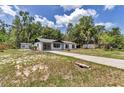 Expansive property featuring a white home, extended driveway, and surrounding wooded area at 6820 Se 108Th St, Belleview, FL 34420