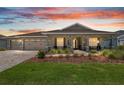 Charming single-story home with manicured front yard, covered porch, and three-car garage at sunset at 9577 Sw 82Nd Street Rd, Ocala, FL 34481