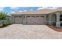 Spacious three-car garage with brick paver driveway and well-maintained landscaping at 9577 Sw 82Nd Street Rd, Ocala, FL 34481