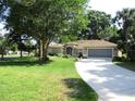 Charming single story home featuring a lush green lawn, mature trees and a two car garage at 14561 Sw 112Th Cir, Dunnellon, FL 34432