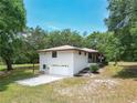 An aerial view of the home highlighting the lawn, two-car garage, wooden patio, and mature landscaping at 2580 Se 157Th Lane Rd, Summerfield, FL 34491