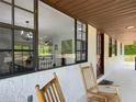 Cozy front porch featuring rocking chairs and large windows offering a glimpse into the dining and living spaces at 2580 Se 157Th Lane Rd, Summerfield, FL 34491