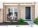A welcoming front porch features rocking chairs, brick accents, and a stylish black front door at 5248 Red Coral Cir, Mount Dora, FL 32757