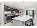 Modern kitchen with black cabinetry, stainless steel appliances, and a large quartz island with bar seating at 5248 Red Coral Cir, Mount Dora, FL 32757