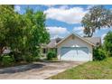 Charming single-Gathering home featuring a light yellow exterior, light blue trim and a two-car garage with a concrete driveway at 8 Juniper Pass Way, Ocala, FL 34480
