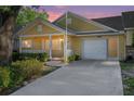 Charming yellow single-story home featuring a covered front porch, one-car garage, and well-maintained landscaping at sunset at 8710 Sw 91St Pl # B, Ocala, FL 34481