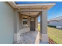 Covered front porch with a tiled floor and a gray front door at 10277 Sw 96Th Loop, Ocala, FL 34481