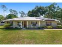 Charming single-story home featuring a metal roof, solar panels, rocking chairs on the porch, and a lush green lawn at 1601 Ne 47Th Ct, Ocala, FL 34470