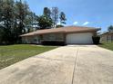 Single-story home with a well-maintained lawn, mature trees, and a large driveway leading to a two-car garage at 7800 Sw 127Th Loop, Ocala, FL 34473