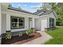 Inviting front exterior with a sidewalk leading to the black trimmed front door at 8293 Se 158Th St, Summerfield, FL 34491