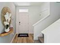 Bright entryway with a decorative mirror, leading to a staircase and showcasing wood-look flooring at 8490 Las Palmas Way, Wildwood, FL 34785
